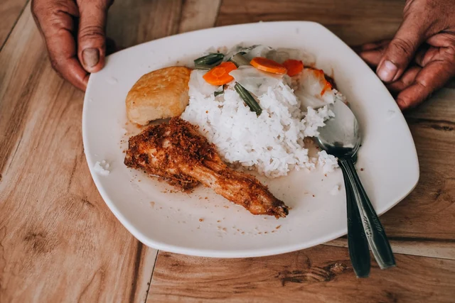 Un piatto con riso, pollo e verdure su un tavolo di legno