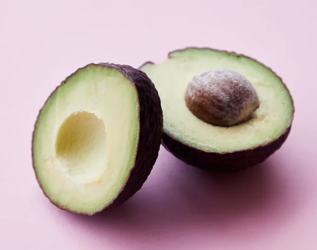 Due metà di avocado maturo su un fondo rosa chiaro