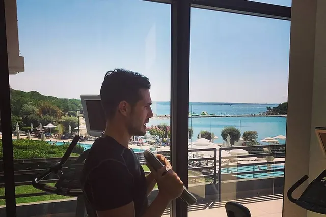 Andrea si allena con un manubrio in una palestra affacciata sul mare