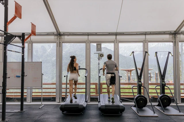 Due persone si allenano su tapis roulant in una palestra luminosa