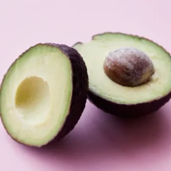 Due metà di avocado maturo su un fondo rosa chiaro