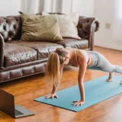Una donna esegue un plank su un tappetino azzurro in casa
