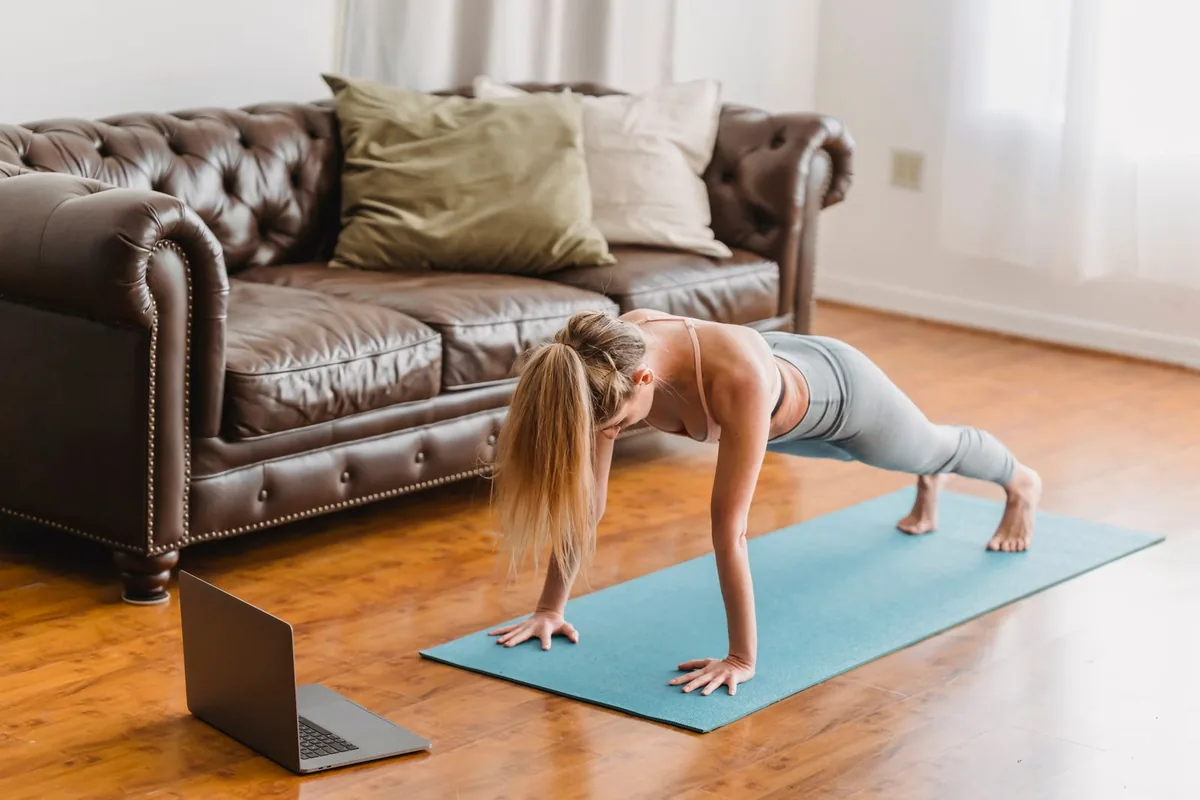 Una donna esegue un plank su un tappetino azzurro in casa